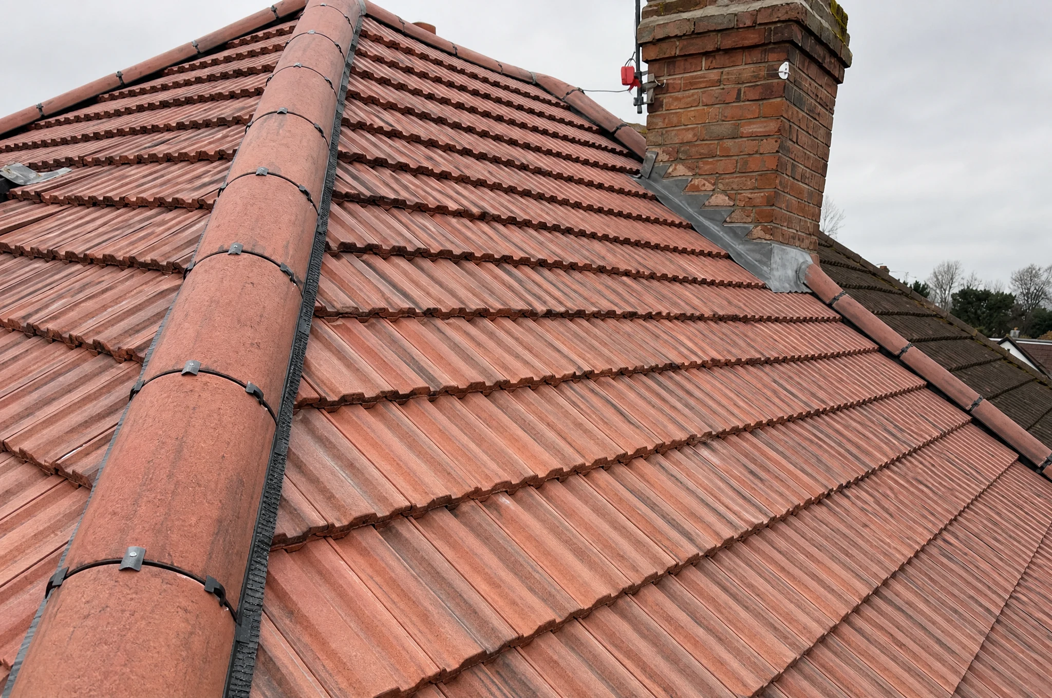 Close-up of a traditional clay tile roof and brick chimney on a period UK property