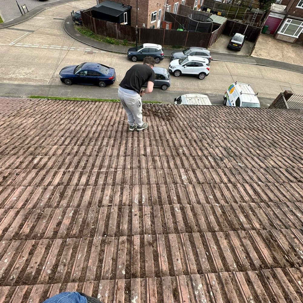 roof tiles being cleaned by man standing on roof